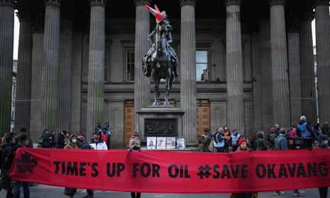 People hold a banner saying Time's Up For Oil