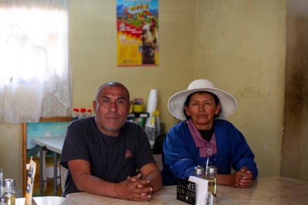 Carlos, wearing a dark T-shirt, and Natividad Mamani, in a blue top and white Andean hat, sat at a table in the restaurant