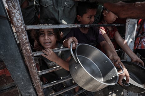 Children wait to receive food in Gaza City, 30 July 2025