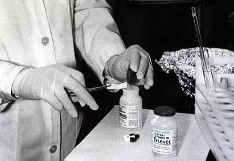 Gloved hands test Tylenol bottles for cyanide using chemically treated paper strips