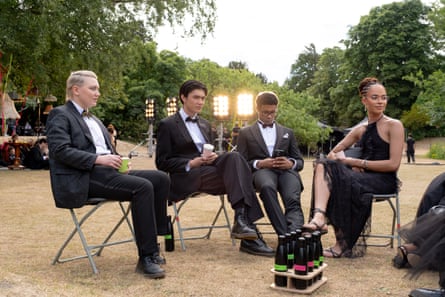 Four young people sit outside on chairs while wearing formal dress.