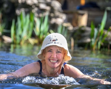 A woman wearing a hat featuring the words Fire & Ice doing breast stroke and smiling at the camera.