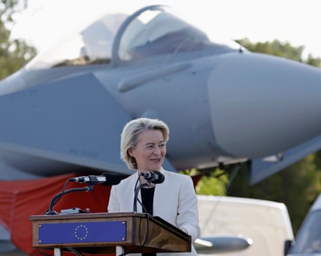 Von der Leyen at a lectern with a jet in the background