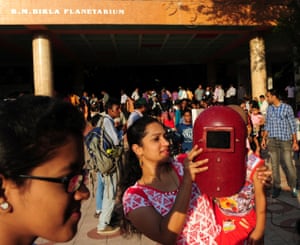 A woman shields her daughters eyes with a welder’s mask at The Birla Planetarium