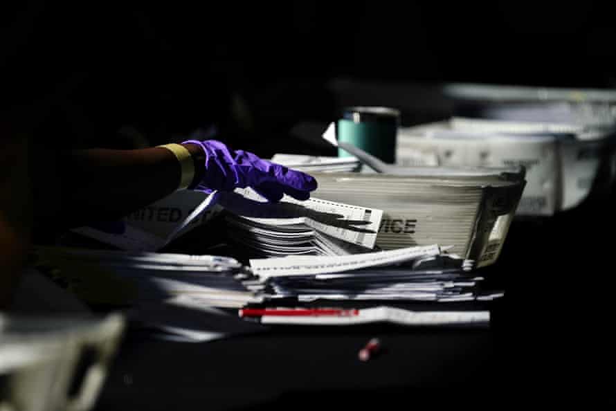 Election personnel handle ballots as vote counting in the general election continues at State Farm Arena in Atlanta.