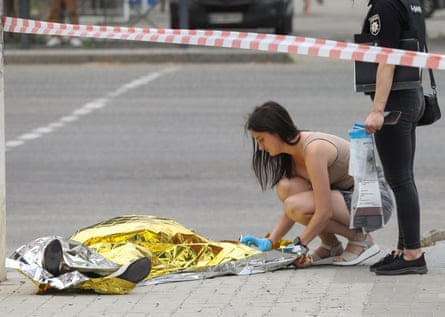 A police forensics expert examines a body on the street in Mykolaiv.