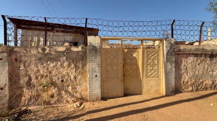 The walls of a compound with barbed wire and metal gates