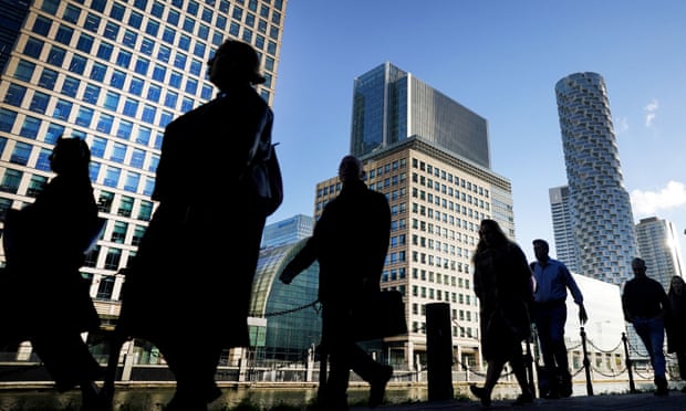 Office workers and commuters walk through Canary Wharf in London during the morning rush hour