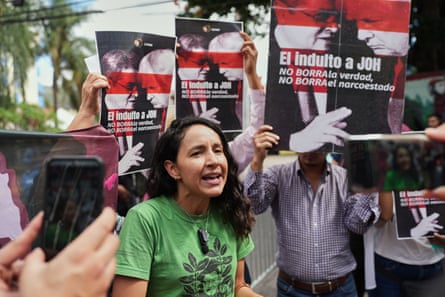 A young woman in a green T-shirt speaks at a protest. Demonstrators placards say ‘El induito a JOH no borra la verdad, no borra el nacroestado’, which roughly translates as ‘the pardon of JOH does not erase the truth, it does not erase the narco-state’.