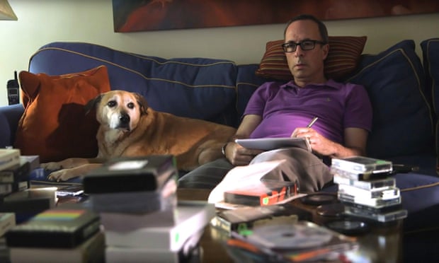 Weide on the couch, surrounded by VHS tapes, with his dog