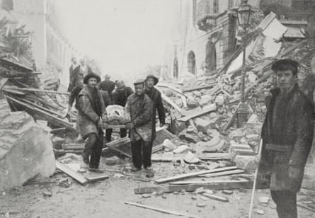 Men carrying a wounded person on a stretcher through the rubble
