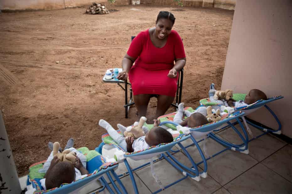 Keneilwe Ditsile alimenta y juega con sus hijos de cuatro patas frente a la casa de su familia en Gaborone, Botswana.