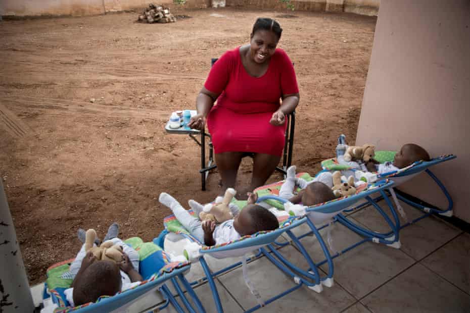 Keneilwe Ditsile alimenta y juega con sus hijos de cuatro patas frente a la casa de su familia en Gaborone, Botswana.