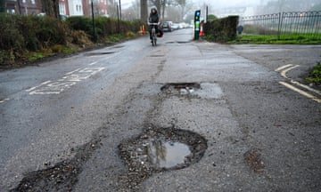 Cyclist approaches huge potholes in road