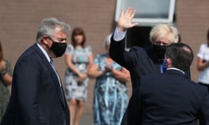 Boris Johnson (C) waves flanked by Northern Ireland Secretary Brandon Lewis (L) and Northern Ireland's Health Minister Robin Swann (R), all wearing facemasks as a precaution against the spread of the novel coronavirus as they arrive to visit the Northern Ireland Ambulance Service HQ in Belfast on 13 August (Photo by Brian Lawless/AFP via Getty Images)