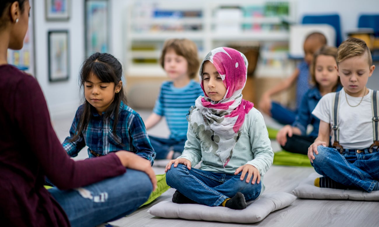 ▲ The Mental Health Foundation wants emotional wellbeing to sit at the heart of school curriculum photography: gettyA multi-ethnic group of young school children are indoors in their classroom. They are sitting on pillows and doing yoga together. They are sitting with their hands in their lap.