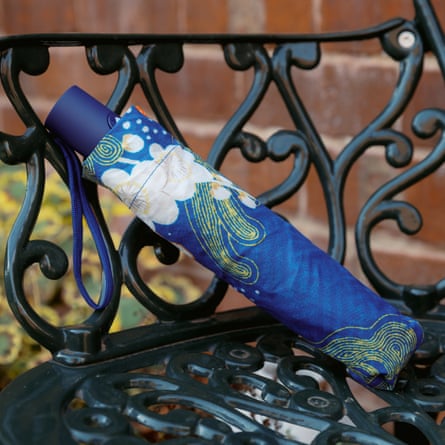 A folded blue floral umbrella rests on an ornate black metal bench