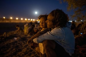 A man back-hugs his young son under a pink moon in Texas