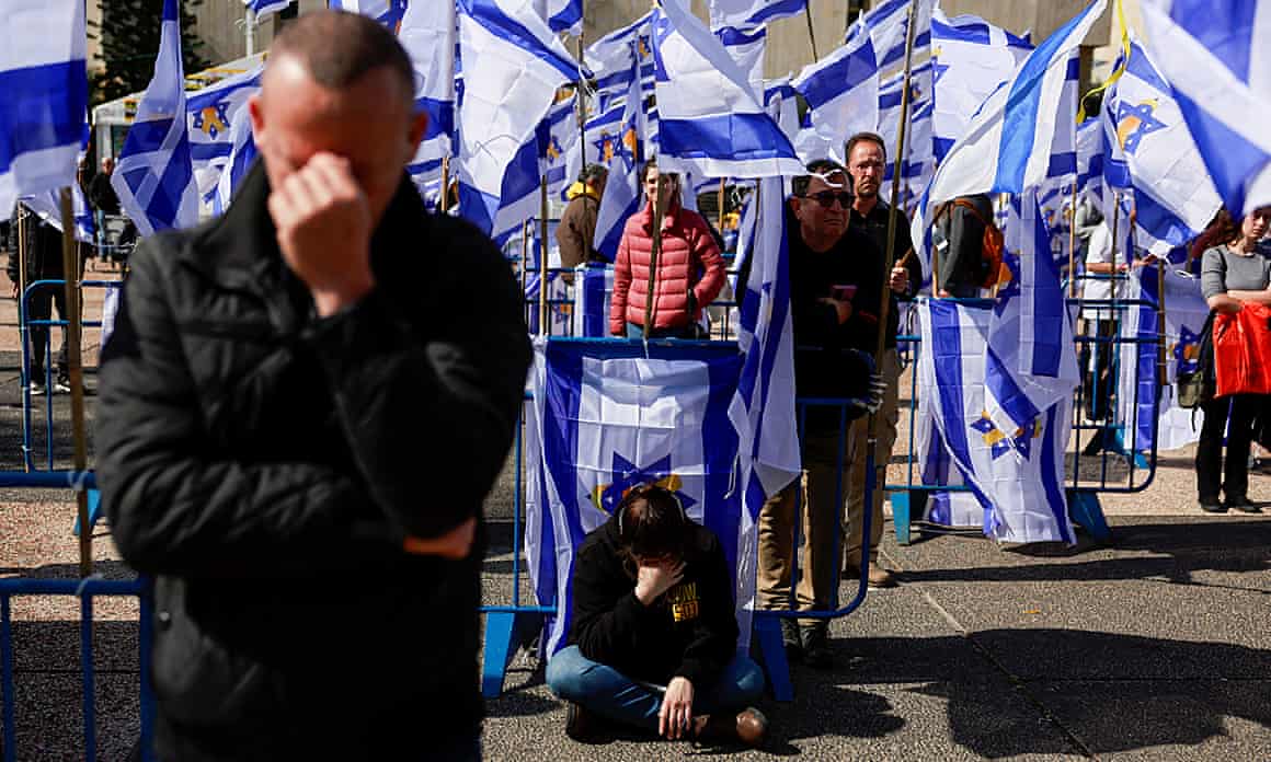 People looking sorrowful against backdrop of Israeli flags