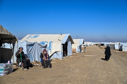 Older men sat outside a tent in the camp sheltering from the sun
