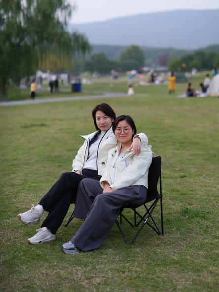 Zhu Danyu with her arm around Fei Yuan as they sit together outdoors