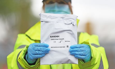 A member of testing staff holds a Randox Covid-19 test kit at a drive-through centre in Belfast.
