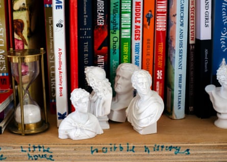 A shelf of children’s books with some white figurines in front of the