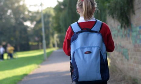 Girl in school uniform and backpack walking in park