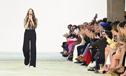 Kamali standing on runway with seated audience applauding to her left