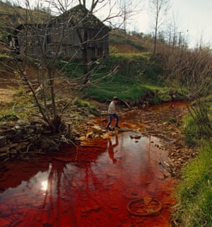 Boy walks across polluted stream which runs by weathered barn on hill, Near Berea, Kentucky