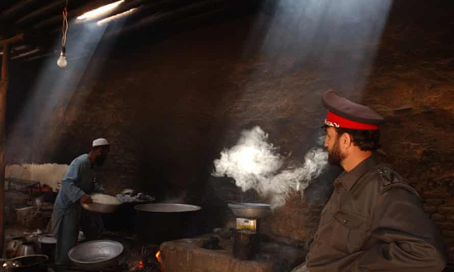 Colonel Abdull Wahed, logistical director of Pol-i Charkhy’s prison, smokes a cigarette as a prison cook prepares lunch for more than 300 prisoners at the jail in Kabul, Afghanistan