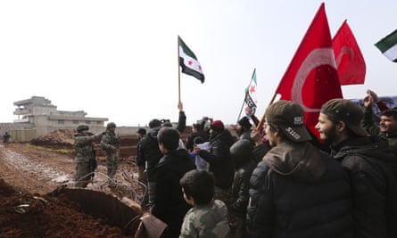 Syrians meet Turkish troops outside their base near the village of Binish, in Idlib province. Turkey, backer of Syria’s opposition, has been deploying equipment and troops in the region, to halt the Syrian military’s advances.