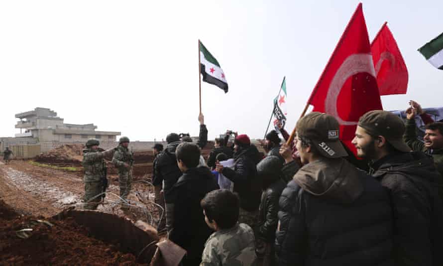 Syrians meet Turkish troops outside their base near the village of Binish, in Idlib province. Turkey, backer of Syria’s opposition, has been deploying equipment and troops in the region, to halt the Syrian military’s advances.