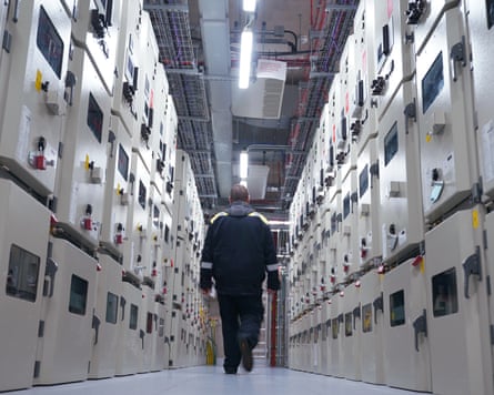 a man walks down a corridor surrounded by huge computer servers