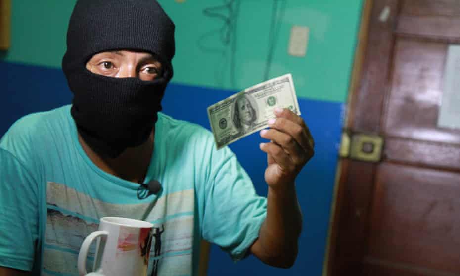 A Peruvian counterfeiter demonstrates the finishing touches to a fake bill.