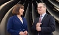 Rachel Reeves and Keir Starmer smile at each other in front of what looks like an enormous black propellor.