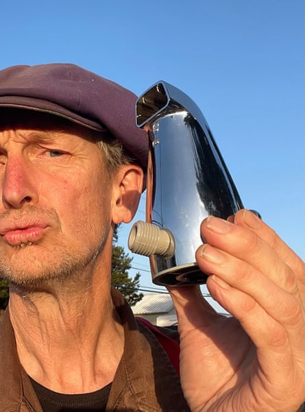 A man holding part of a faucet outdoors.