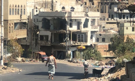 People walking and cycling on road with destroyed building in background