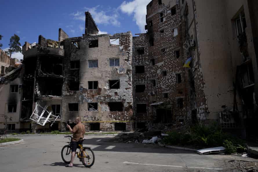 A man on a bicycle takes pictures of damaged buildings ruined by attacks in Irpin, on the outskirts of Kyiv, Ukraine.