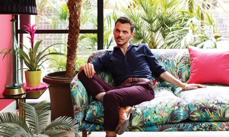 Matthew Williamson sitting on a sofa upholstered in one of his Osborne & Little fabrics.
