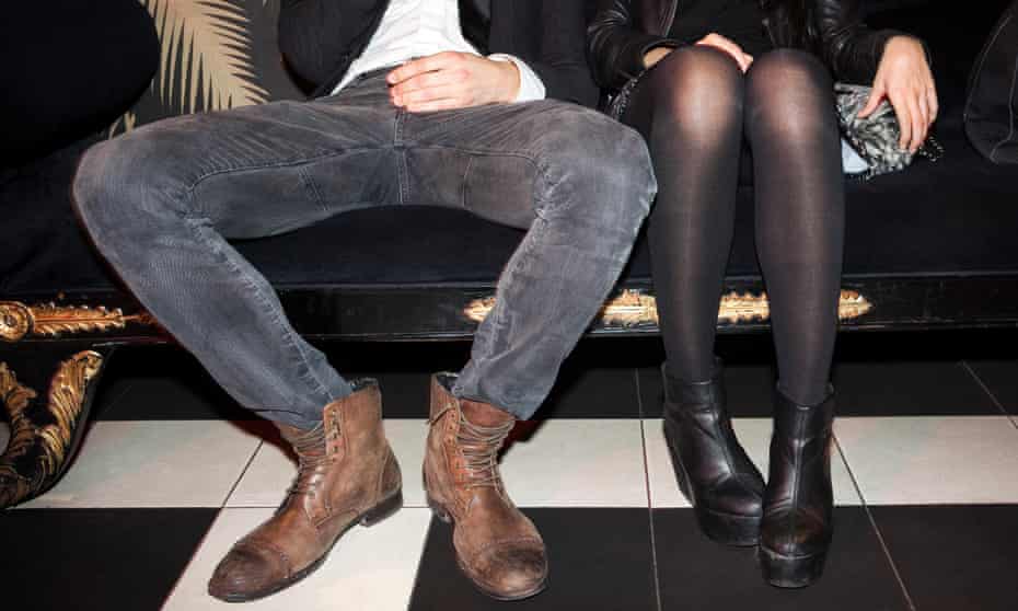 Young couple sitting side by side at nightclub manspreading