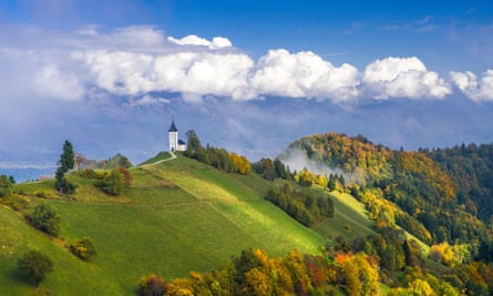 Amid a mountain and forest landscape, a view of the church of St Primus and Felicianus in Jamnik, Slovenia.