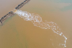 A broken sea wall spills sea water on to aquaculture farmland next to Bohai Bay