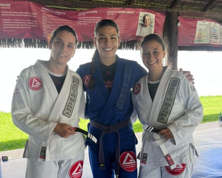 Three women in martial arts gear in a sports studio setting