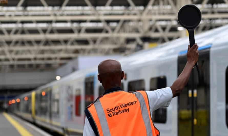 A rail worker at Waterloo Station hold a dispatch baton ahead of strikes that disrupt trains across the UK.