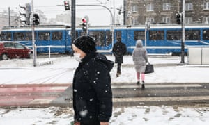 A woman walks in a snowfall in Krakow, Poland, on January 17 as the country's health minister warned the Omicron version could spike the number of daily cases.