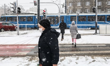 A woman walks in the snowfall in Krakow, Poland on 17 January as the country’s health minister warns the Omicron variant could send daily case numbers soaring.