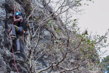 A man climbing on a vertical rockface using ropes and harness.