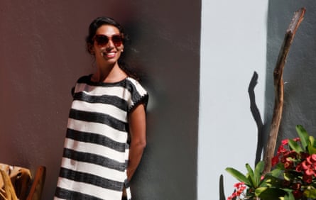A woman in sunglasses stands in the sun in a black and white striped dress