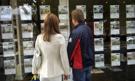 Young people looking in estate agent window